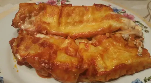 Cannelloni ricotta e carne gratinati al forno, con sugo rosso e formaggio filante.