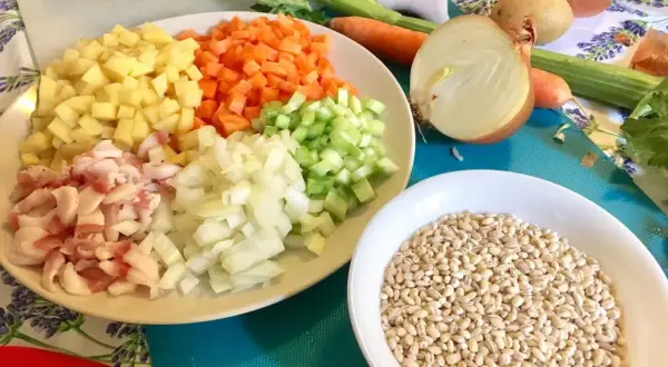 Ingredienti pronti per una saporita minestra d'orzo: orzo perlato, patate, carote, sedano, cipolla e pancetta.
