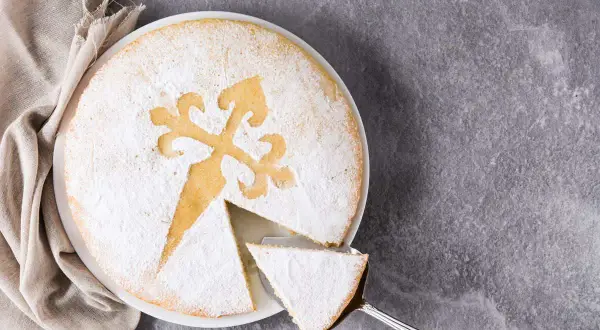 Una fetta di torta di Santiago, cosparsa di zucchero a velo, con la tipica croce incisa.