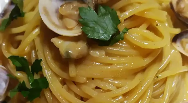 Spaghetti alle vongole cremosi come al ristorante, un piatto invitante con pasta dorata, vongole succulente e prezzemolo fresco.