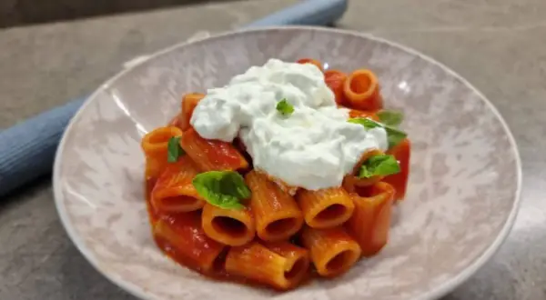 Rigatoni al sugo con abbondante stracciatella cremosa e basilico fresco. Un piatto semplice ma delizioso.