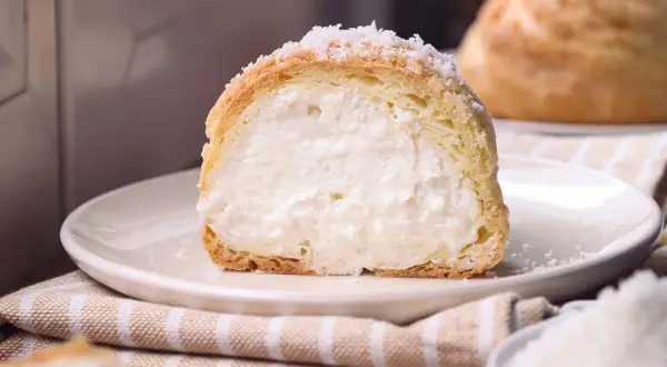 Bignè ripieno di crema soffice, cosparso di zucchero a velo che ricorda fiocchi di neve.