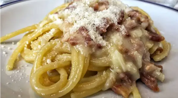 Un piatto di spaghetti alla carbonara, cremosi e ricchi di guanciale croccante, spolverati di pecorino.