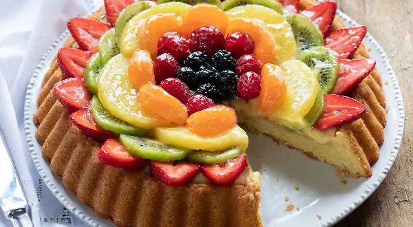 Una deliziosa crostata morbida alla frutta, con fragole, kiwi, mandarini e frutti di bosco su una base soffice e crema pasticcera.
