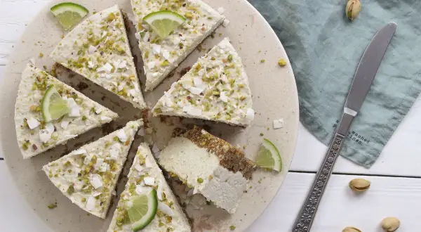 Deliziosa cheesecake vegana con lime e pistacchi, guarnita con scaglie di cocco.