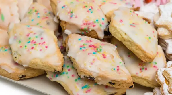 Un vassoio pieno di dolci sardi, biscotti ricoperti di glassa bianca e confettini colorati, perfetti per ogni occasione.