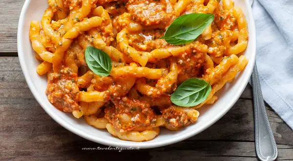 Busiate alla trapanese, pasta fresca con sugo rosso e basilico, un piatto ricco di sapori mediterranei.