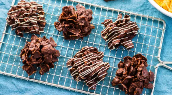Sei deliziose rose del deserto al cioccolato, alcune decorate con glassa bianca, riposano su una griglia.