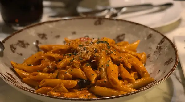 Penne al dente condite con una ricca crema di melanzane, guarnite con parmigiano e prezzemolo. Un piatto invitante per un pranzo gustoso.