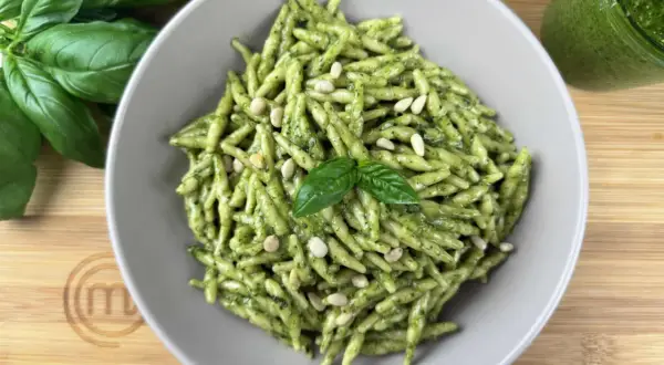 Piatto di trofie al pesto, guarnite con pinoli e basilico fresco. Un classico delle trofie ricette, pronto da gustare.