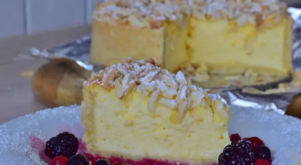 Una fetta di torta di riso ricetta originale, guarnita con mandorle e frutti di bosco, su un piatto bianco.