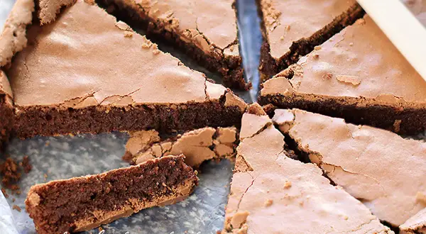 Fetta di torta tenerina, con la sua crosticina croccante e il cuore morbido e cioccolatoso, pronta per essere gustata.