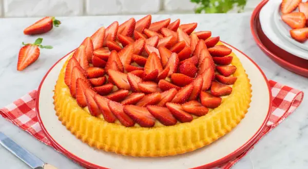 Deliziosa crostata di fragole, con una base dorata e un ripieno cremoso, ricoperta da fragole fresche affettate.