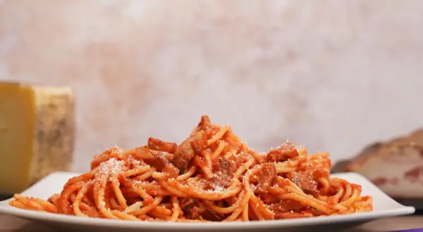 Un piatto di spaghetti conditi con sugo rosso e guanciale croccante, un assaggio dell'amatriciana ricetta originale di Amatrice.