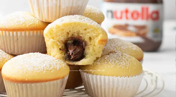 Muffin soffici con cuore di Nutella, perfetti per chi ama le ricette dolci. Un vasetto di Nutella sullo sfondo.