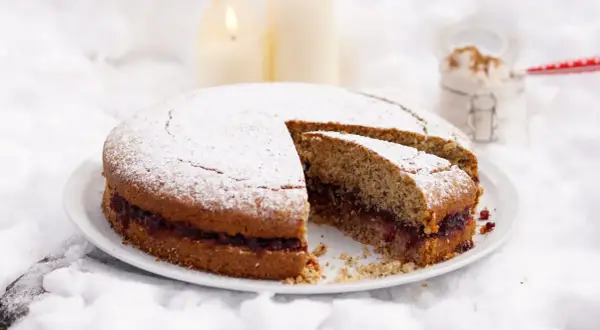 Torta di grano saraceno trentino con marmellata, spolverata di zucchero a velo, su un letto di neve e candele accese.