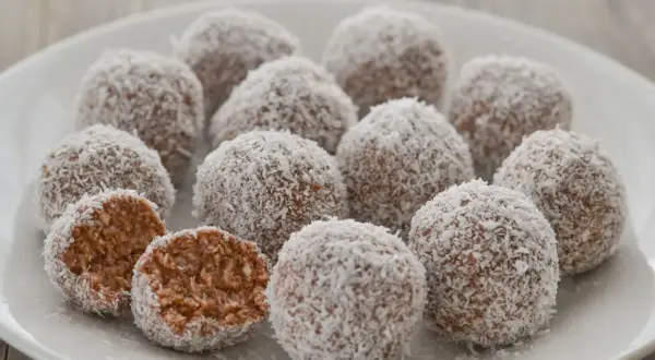 Dolci palline di cocco, una delizia da gustare in ogni momento. Una è stata aperta, rivelando il suo interno morbido e invitante.