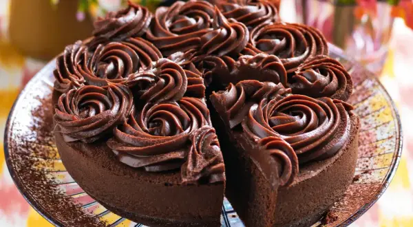 Una deliziosa torta al cioccolato, ricoperta da rosette di crema al cioccolato, con una fetta mancante che invita a un assaggio goloso.