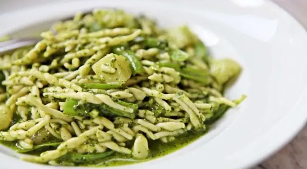 Un piatto di trofie al pesto, un classico della cucina ligure, con un condimento verde brillante e saporito.