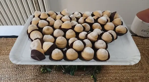 Dolcetti "tette delle monache" spolverati di zucchero a velo, un'antica ricetta che narra storie di conventi e sapori autentici.