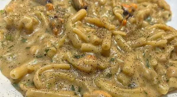 Un piatto cremoso di pasta fagioli e cozze, condito con prezzemolo fresco e pepe nero macinato.