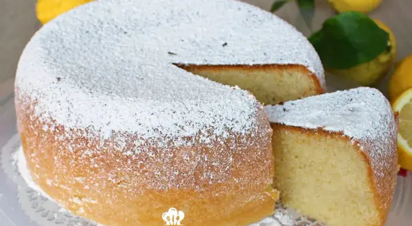 Torta al limone morbidissima e profumatissima benedetta, cosparsa di zucchero a velo. La fetta tagliata rivela la sua sofficità.