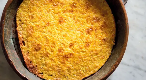Farinata di ceci appena sfornata, dorata e croccante, in una teglia di rame. Una deliziosa ricetta da provare subito!