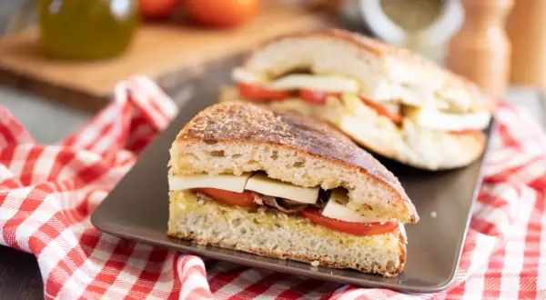 Pane cunzato con pomodoro, formaggio e acciughe, pronto per essere gustato.