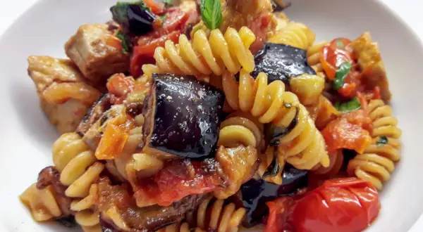 Fusilli con pesce spada, melanzane, pomodorini e basilico, un piatto estivo saporito.