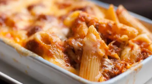 Un invitante piatto di pasta al forno, con penne ricoperte da un ricco sugo e abbondante formaggio fuso, pronto per essere gustato.