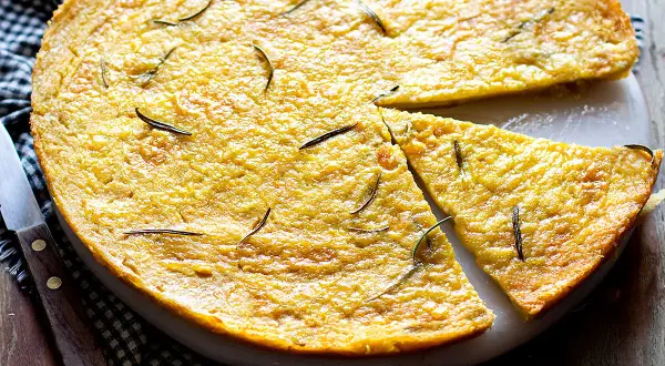 Dorata farinata di ceci in padella, guarnita con rosmarino fresco, pronta per essere gustata.
