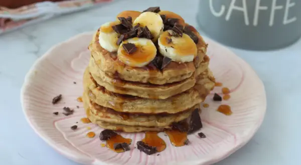 Pancake banana e yogurt, una pila golosa con scaglie di cioccolato e sciroppo d'acero.
