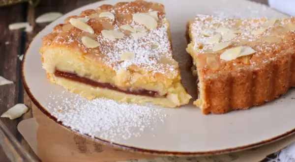 Fette di crostata frangipane con marmellata e mandorle, spolverate di zucchero a velo.