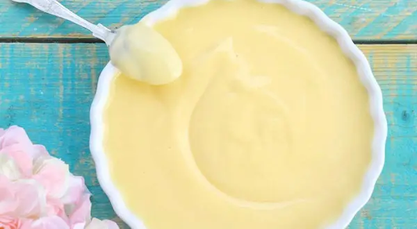 Crema pasticcera ricetta della nonna, liscia e vellutata, pronta per essere gustata. Un cucchiaio d'argento ne assapora la bontà.