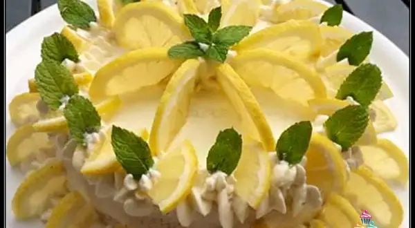 Delizia al limone, una torta fresca e profumata, decorata con fette di limone e foglie di menta.
