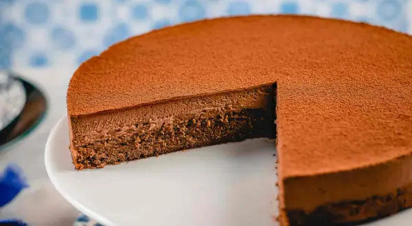 Una deliziosa torta Lisbona al cioccolato, con una soffice mousse e una base croccante, spolverata di cacao.