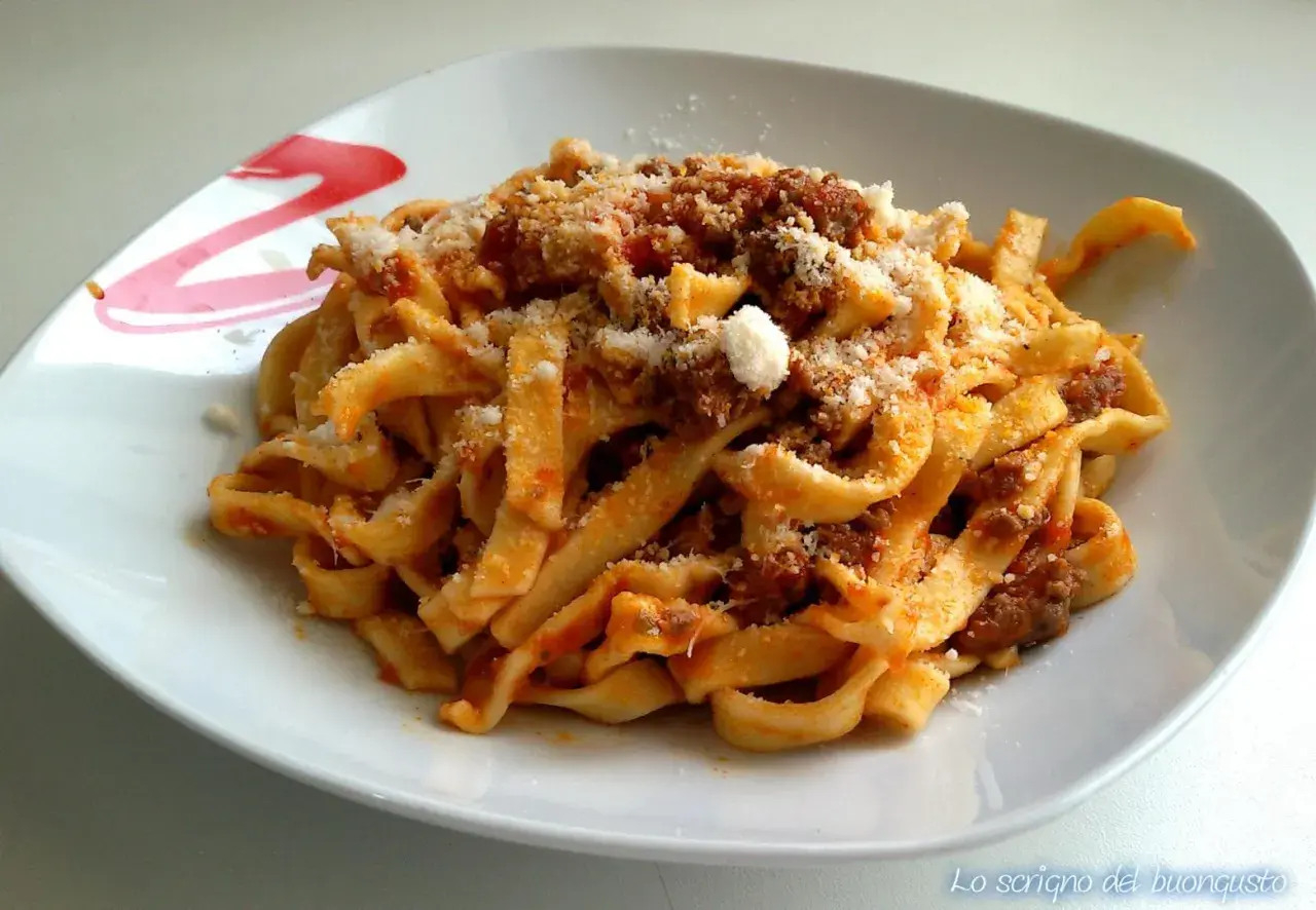 Un piatto invitante di tagliatelle al ragù, condite con abbondante parmigiano grattugiato.