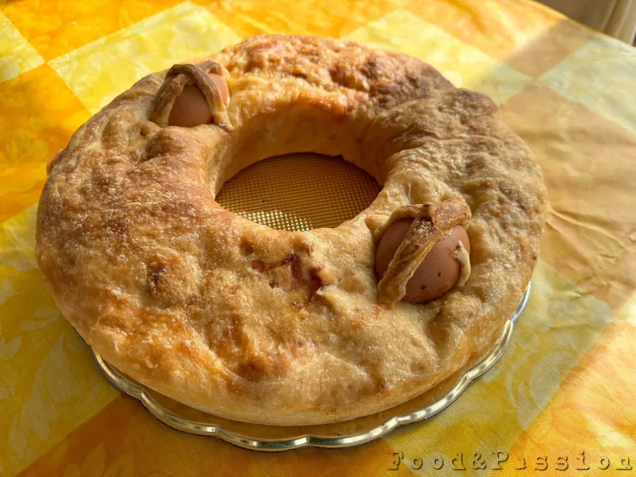 Casatiello napoletano dorato, con uova intere incastonate nell'impasto, pronto per essere gustato.