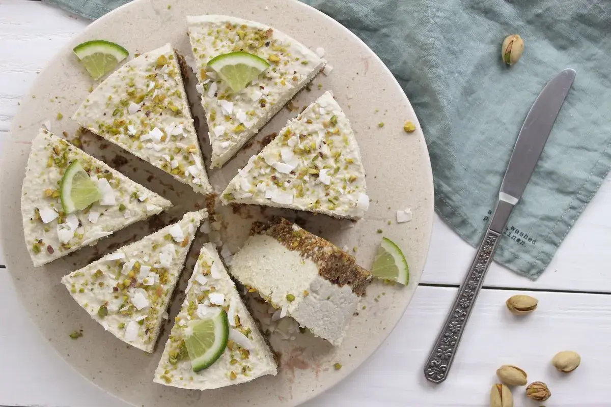 Deliziosa cheesecake vegana con lime e pistacchi, guarnita con scaglie di cocco.