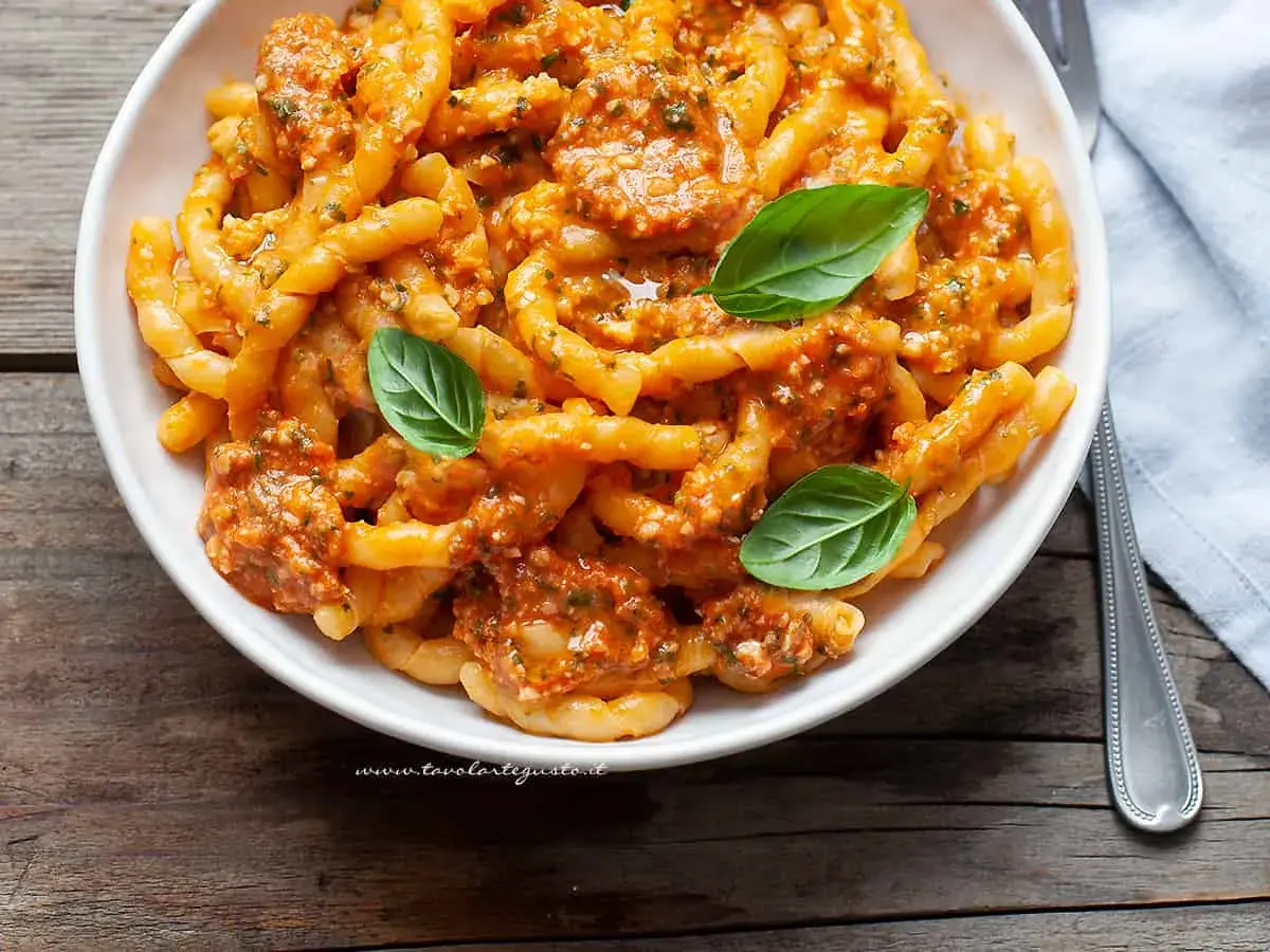 Busiate alla trapanese, pasta fresca con sugo rosso e basilico, un piatto ricco di sapori mediterranei.