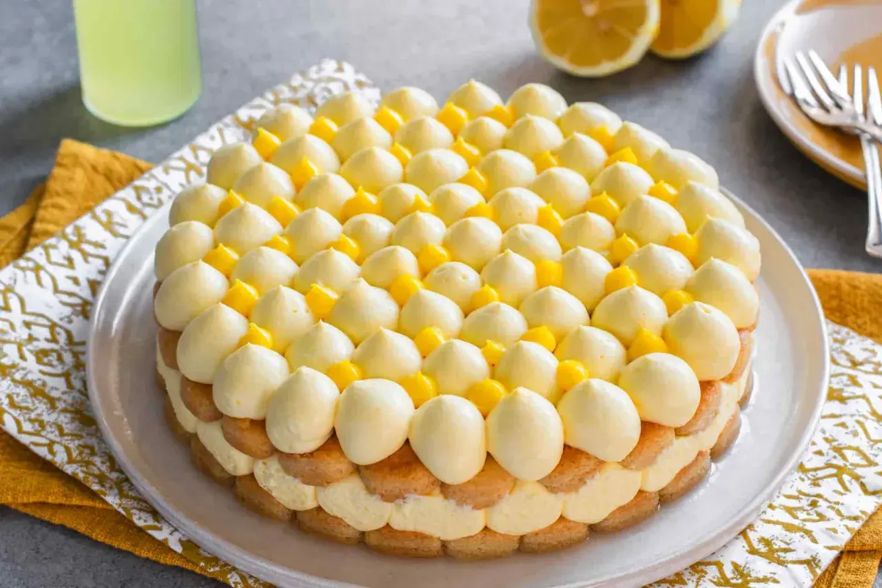 Delizioso tiramisù al limoncello, con strati di savoiardi, crema al limone e decorazioni di panna e cubetti di limone.
