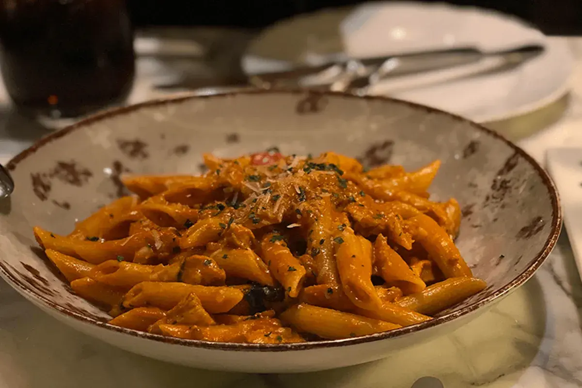 Penne al dente condite con una ricca crema di melanzane, guarnite con parmigiano e prezzemolo. Un piatto invitante per un pranzo gustoso.