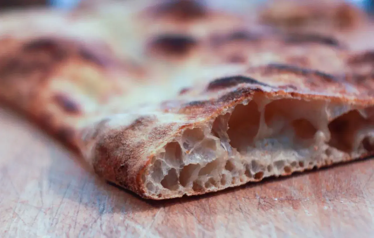 La pizza bonci, con la sua alveolatura perfetta e la crosta dorata, è un'opera d'arte culinaria.
