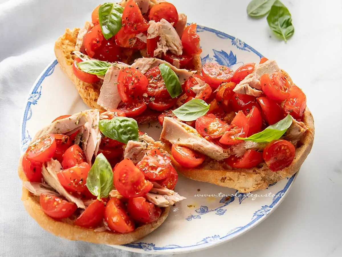Friselle con pomodorini freschi, tonno e basilico, un piatto estivo leggero e gustoso.