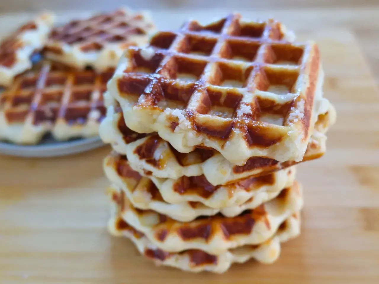 Una pila di waffle dorati, con la loro tipica griglia, che ricordano la waffle ricetta originale belga.