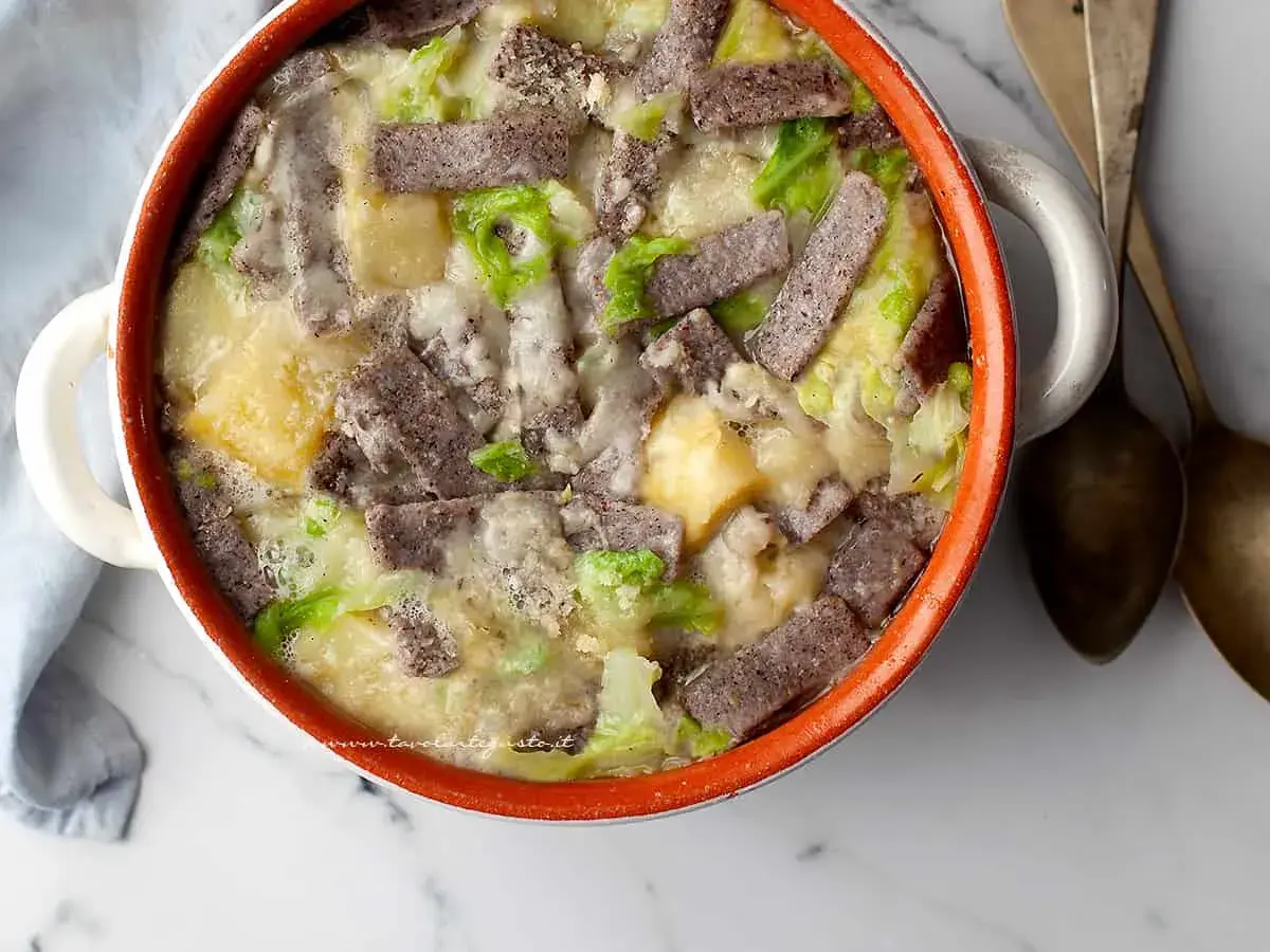 Pizzoccheri ricetta: un piatto fumante in una casseruola con pasta di grano saraceno, patate, verza e formaggio fuso.