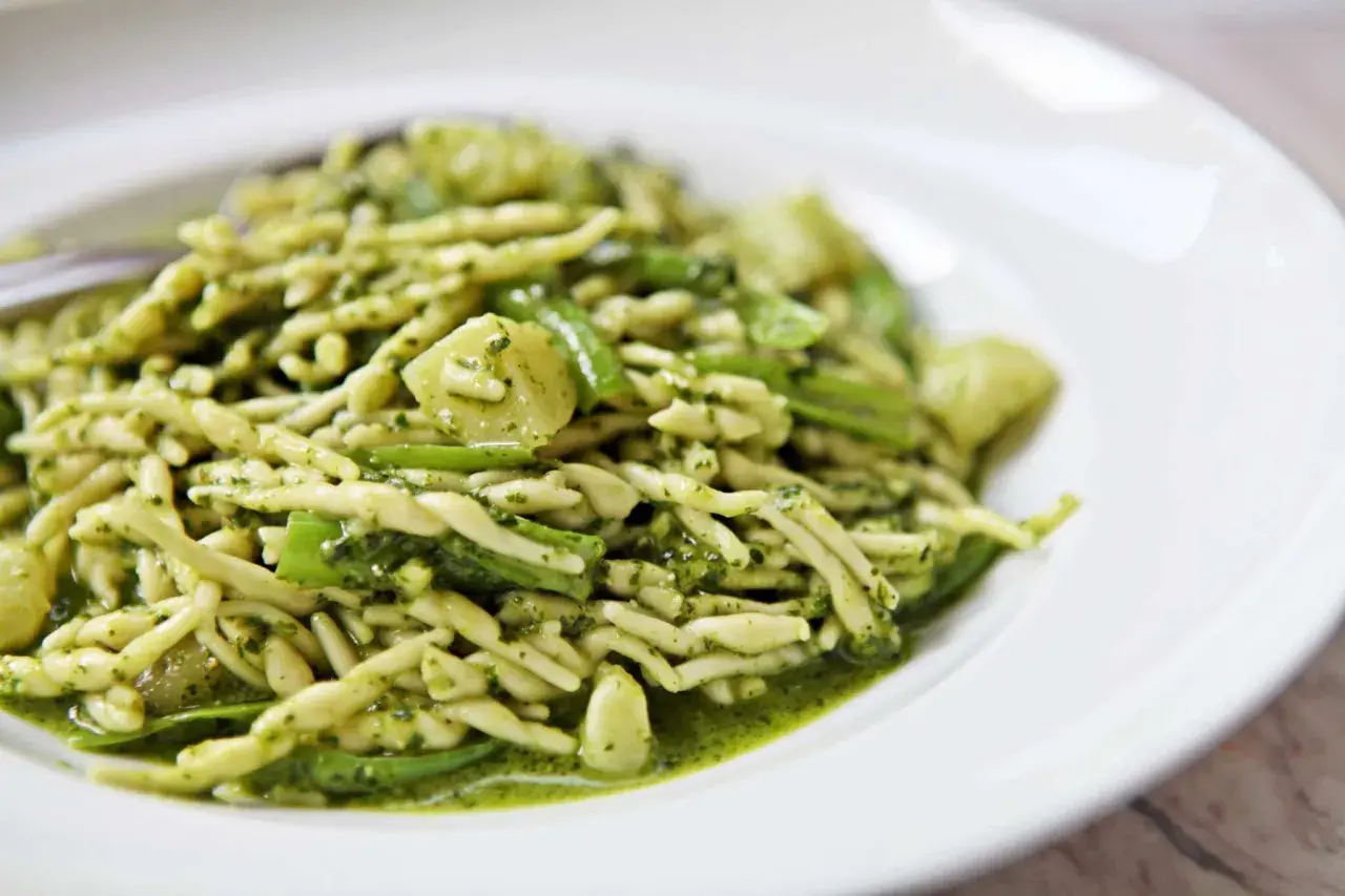 Un piatto di trofie al pesto, un classico della cucina ligure, con un condimento verde brillante e saporito.