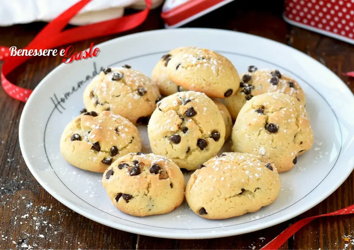 Biscotti con gocce di cioccolato, spolverati di zucchero a velo, su un piatto bianco con scritta