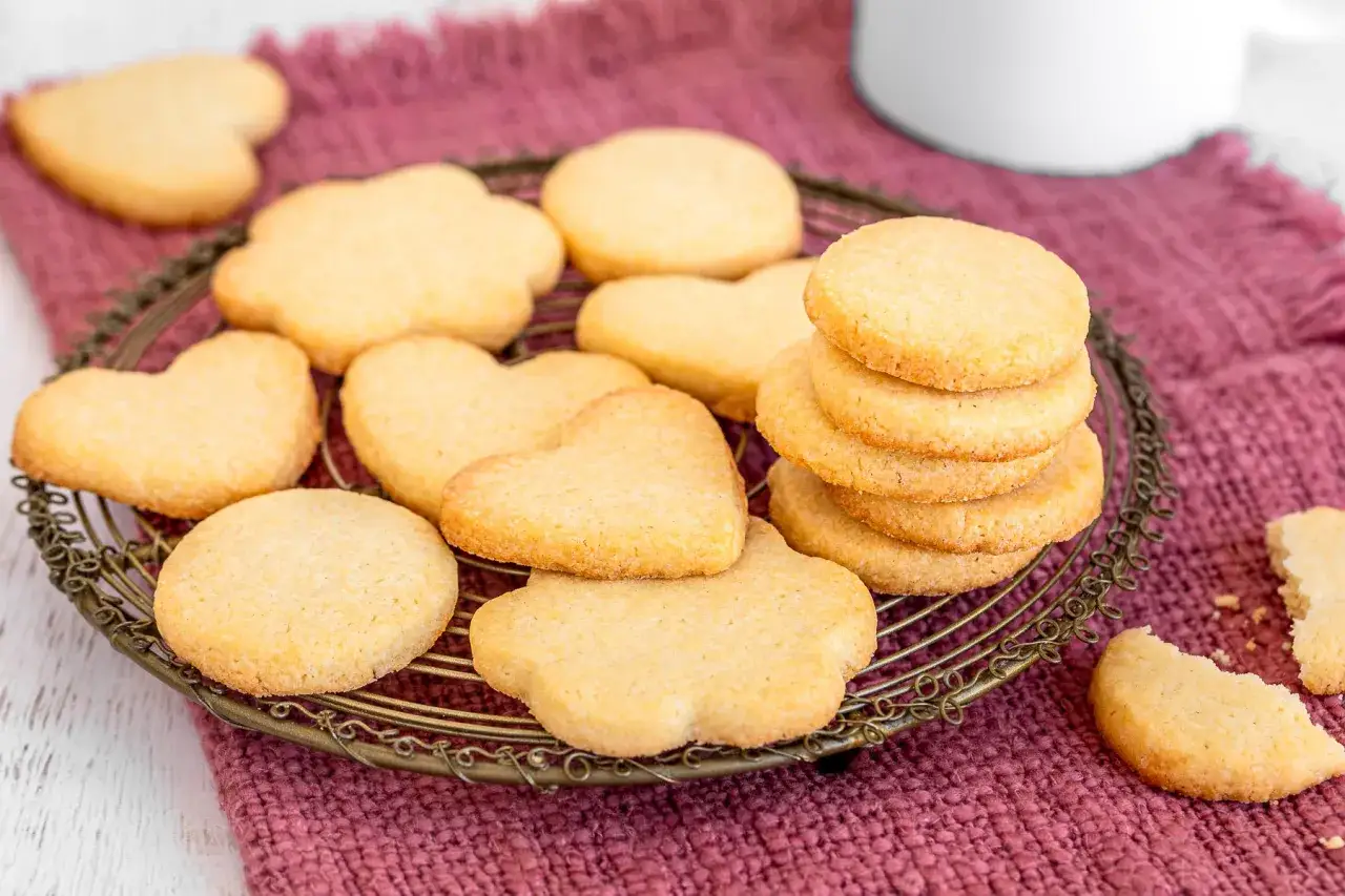 Deliziosi dolci per colazione a forma di cuore e fiore, serviti su un cestino dorato.