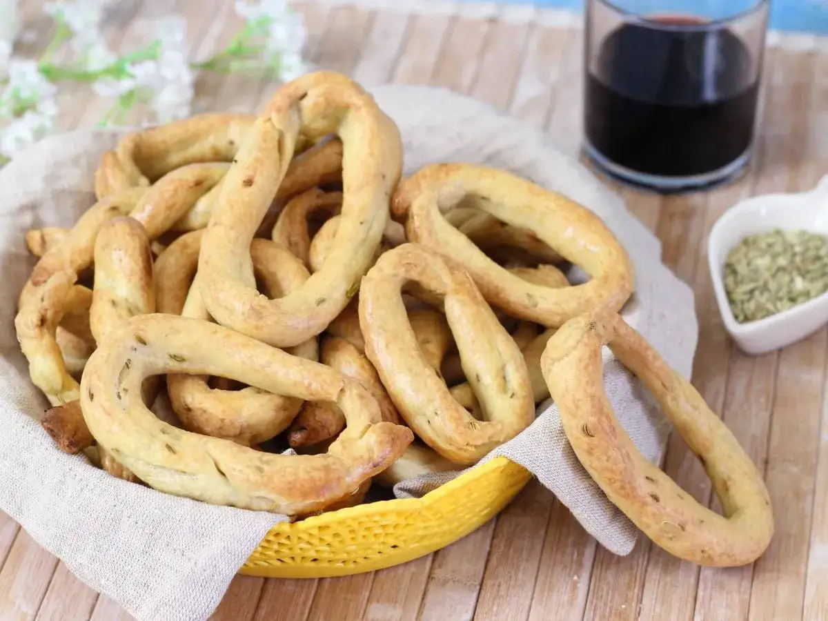 Taralli al finocchietto con lievito, dorati e fragranti, in un cestino, pronti per essere gustati con un bicchiere di vino rosso.